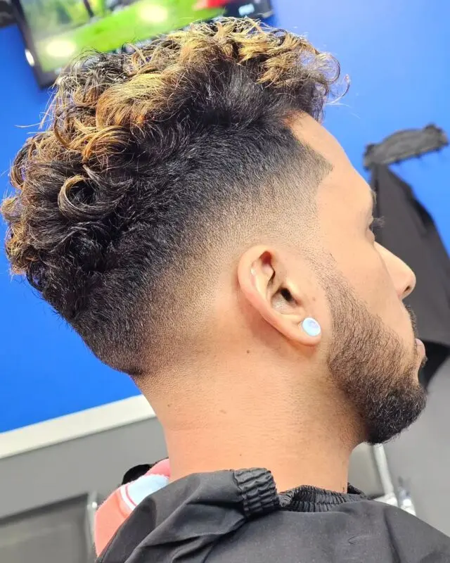 Curly top with blonde tips over a taper fade